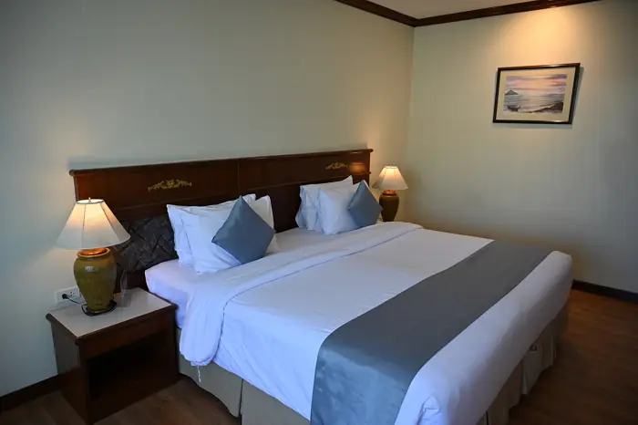 A neatly made hotel bed with white linen and soft pillows